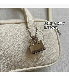 Close-up of off-white lychee grain leather texture with a silver mini bag charm detail