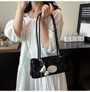 Dettaglio della borsa a spalla in jacquard nero con trama a trifoglio e fiocco