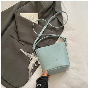 Detail of mint blue bucket bag with lychee grain leather and lace pearl pendant
