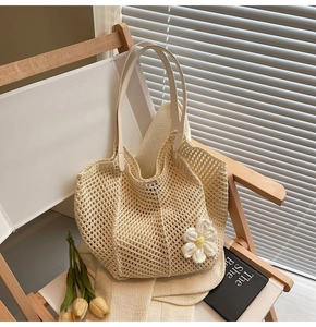 Detail of cream woven tote bag featuring mesh texture and decorative white floral charm