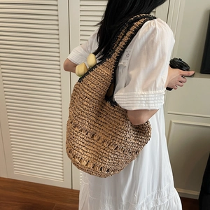 Detail of the natural woven texture and contrasting black straps on a large straw tote bag