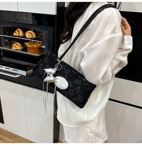 Dettaglio della borsa a spalla jacquard nera con ciondolo a fiocco argento e tracolla a catena