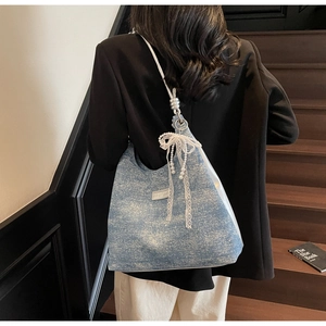 Detail of blue denim tote bag with glitter finish and lace pearl bow on wooden stairs