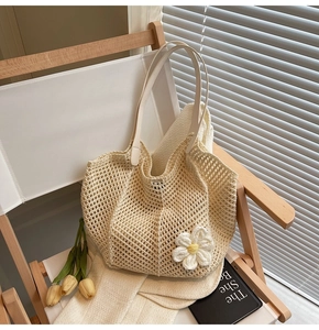 Detail of hand-woven beige straw tote bag featuring a large crochet daisy flower