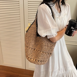 Detail of handwoven straw tote bag featuring contrast stitching and cut-out texture