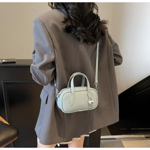 Detail of light blue pebble leather Boston bag with metal lock and crossbody strap