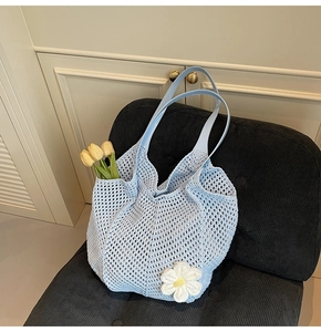 Detail of light blue crochet tote bag with daisy ornament on a black velvet chair