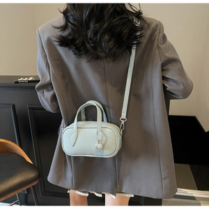 Detail of light blue pebble leather handbag with silver lock charm on a grey blazer
