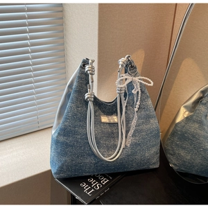 Détail du sac cabas en denim avec poignée chaîne argentée et nœud en dentelle perlé