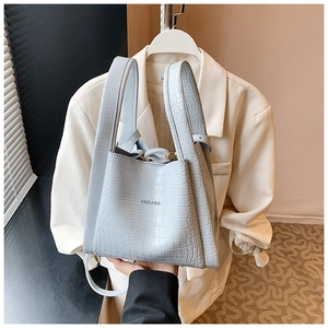 Detail of baby blue crocodile pattern handbag with HMOAIRD logo and top handles