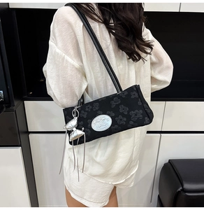 Dettaglio borsa baguette nera con goffratura floreale 3D e ciondolo a fiocco argento