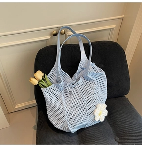 Detail of light blue crochet woven tote bag with white floral charm and tulip decoration