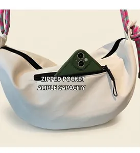 Detalle del bolso de media luna blanco con bolsillo de cremallera y móvil verde