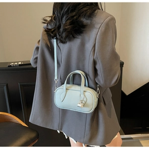 Close-up of light blue mini pillow bag with litchi grain texture and silver lock pendant