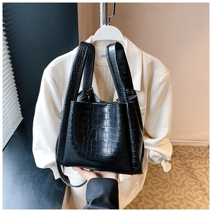 Detailed close-up of glossy black crocodile pattern texture on a sleek bucket handbag