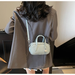 Litchi pattern leather crossbody bag in light blue shown on model with silver lock detail