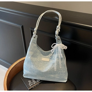 Détail du sac hobo en denim à paillettes bleu clair avec nœud en dentelle et poignée