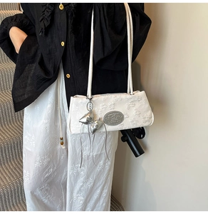 Dettaglio borsa sottospalla bianca con ricamo farfalla 3D e ciondolo a fiocco argento