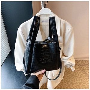 Close-up of black crocodile pattern faux leather tote bag showing texture and hand strap