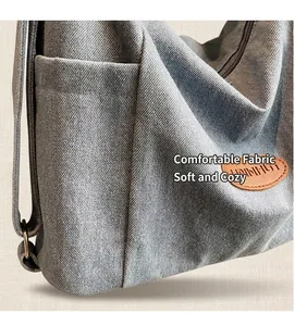 Detail of light blue denim tote bag featuring side pocket and brown leather logo patch