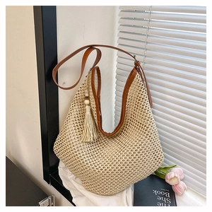 Detail der Boho-Stroh-Tote-Tasche mit braunen Ledergriffen und Holzperlen-Quaste