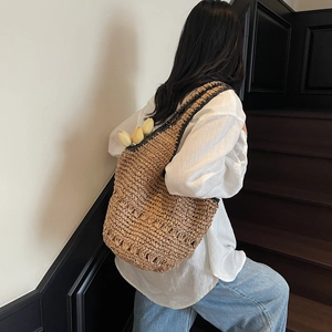 Close-up of beige woven straw tote bag featuring intricate openwork textures and strap detail