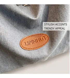 Macro shot of a brown leather patch with embossed logo on light blue denim tote bag
