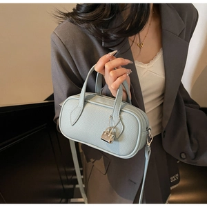 Detail of light blue lychee pattern leather mini bag with silver lock and shoulder strap