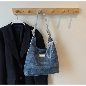 Détail du sac bandoulière en denim bleu avec paillettes, nœud en dentelle et sangle