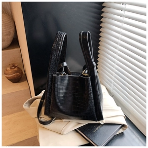 Detail of black crocodile texture faux leather handbag with gold metal buckles and strap