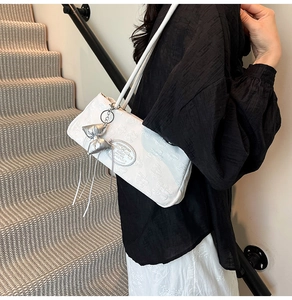Dettaglio della borsa sottobraccio in nylon bianco con trama floreale 3D e ciondolo a fiocco