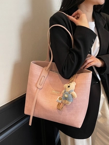 Pink woven tote bag with a cute plush bear pendant shown on model for daily commuting