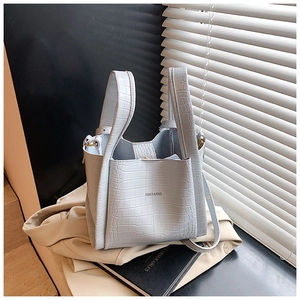 Detail of light blue croc-effect bucket bag showing texture and top handles