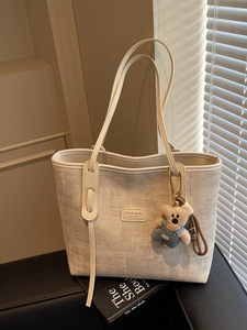 Chic woven tote bag in oatmeal beige with leather trim and cute plush bear charm
