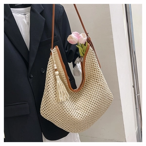 Detail der gewebten Stroh-Tasche mit braunem Lederbesatz und dekorativen Holzperlen-Quasten