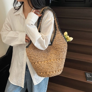 Detail of straw tote bag showing intricate woven texture and black braided trim accents