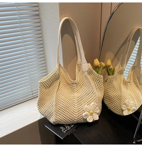 Detail of hand-woven mesh tote bag with a white daisy flower and leather straps
