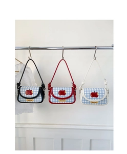 Detail of grid texture shoulder bags featuring red apple embroidery and knot straps