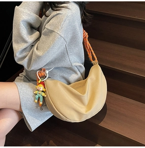 Bolso de lona beige con correa de cuerda naranja y colgante de muñeca en escaleras de madera