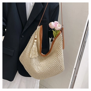Detail einer geflochtenen Strohtasche mit braunem Rand und beigefarbener Quaste mit Holzperlen