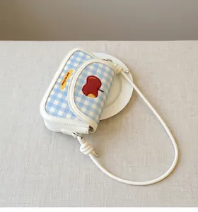 Close-up of blue plaid crossbody bag with red apple and yellow banana embroidery