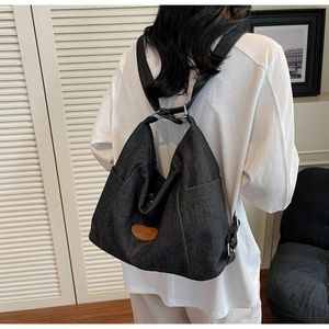 Detail of grey denim tote bag showing the leather logo patch and spacious side pocket