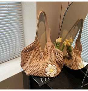 Detail of knit hollow tote bag featuring a 3D white flower and brown leather handle