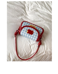 Detail of red apple patch with 'not anxious' text and blue plaid fabric on small bag