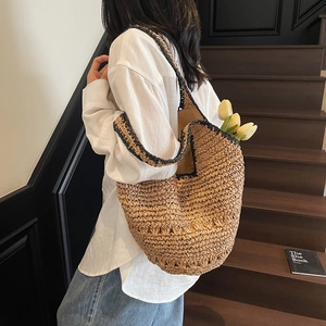 Detail of large woven straw tote bag with black edge trim and casual vacation style