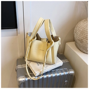 Detail of light yellow crocodile pattern handbag with detachable shoulder strap and handles