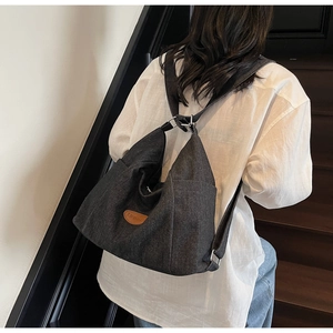Detail of gray denim tote bag featuring a leather logo patch and side pocket design