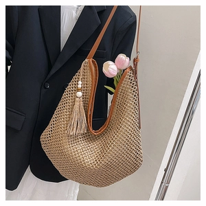 Detail der hohlen Strohtasche mit braunem Lederbesatz und böhmischem Fransen-Anhänger