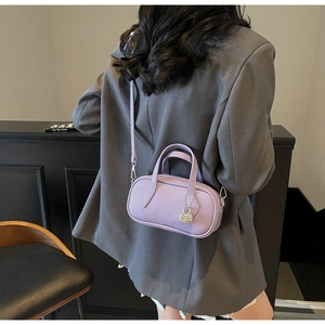 Detail of light purple litchi grain leather bag worn over a grey blazer