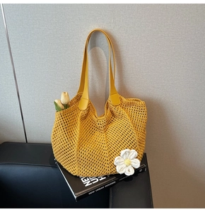 Detail of yellow woven tote bag featuring hollow texture and crochet flower accent